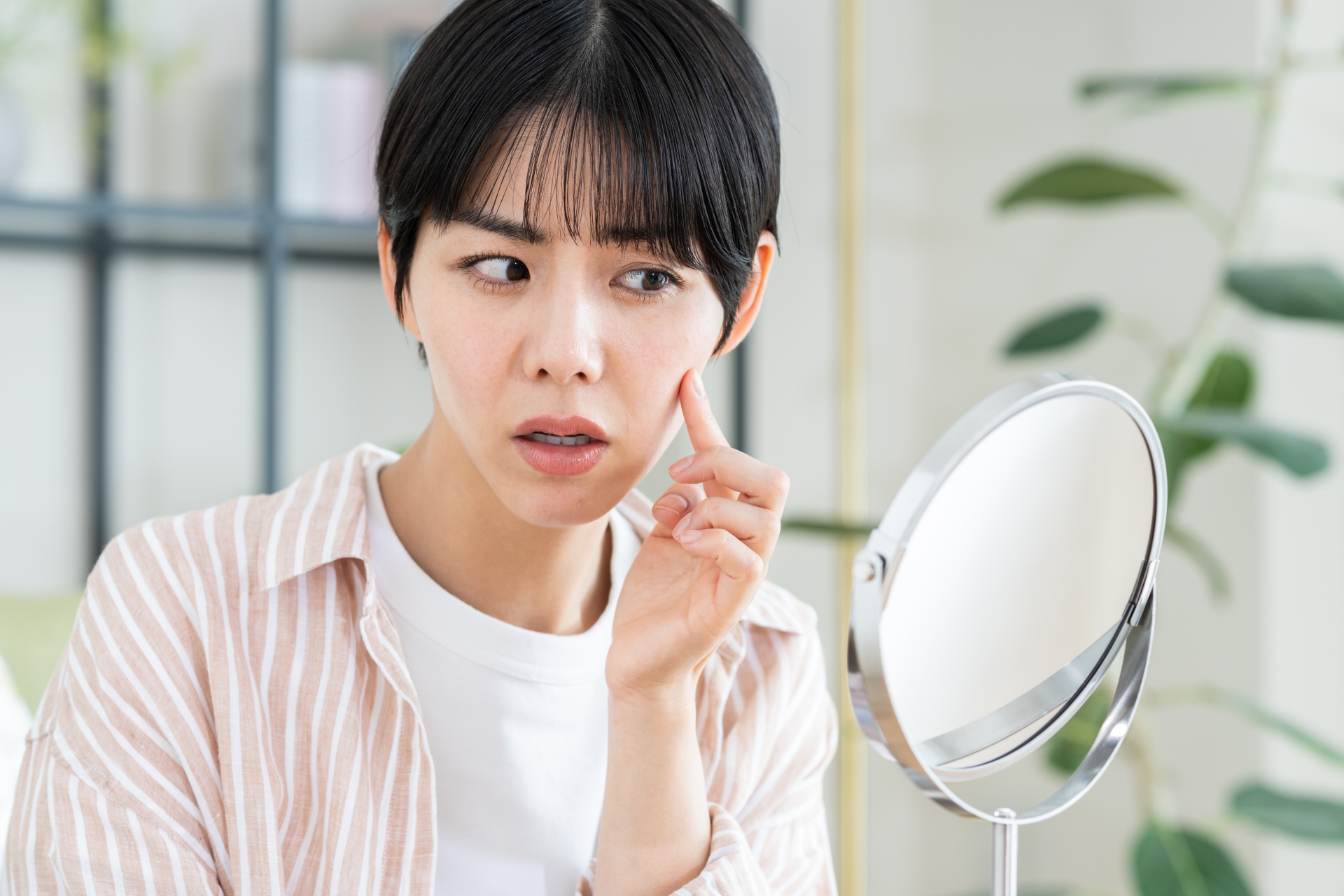 鏡で顔をチェックする女性